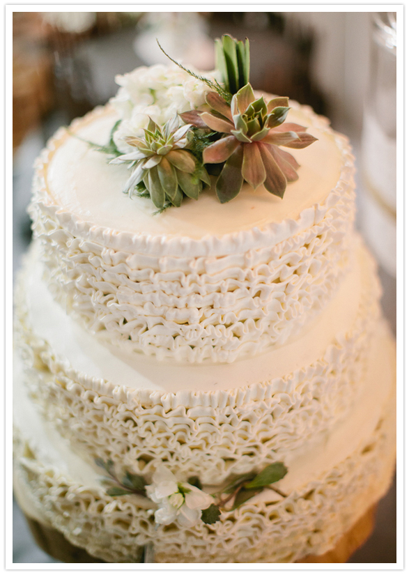 white ruffled wedding cake and succulent topper