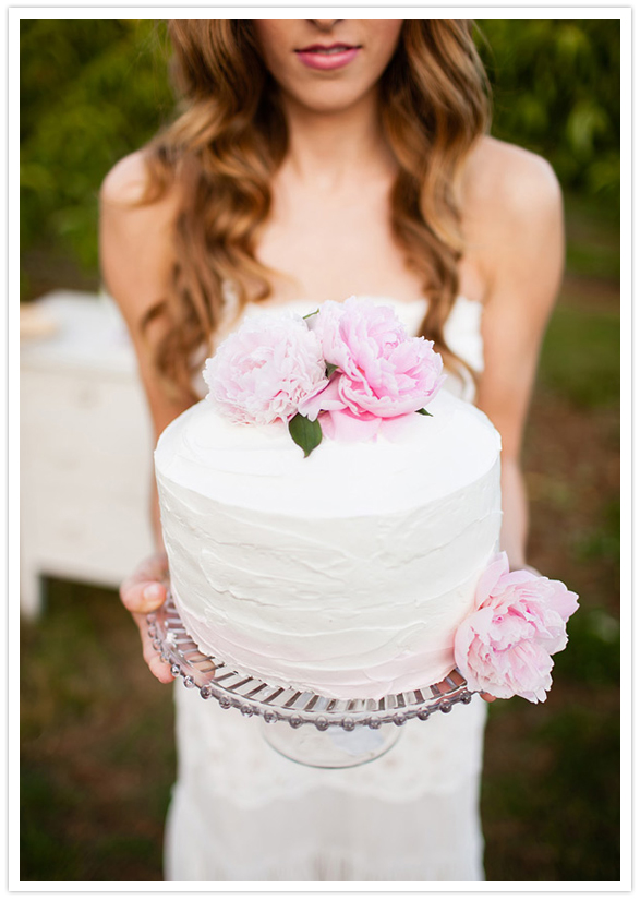 pink peony adorned white frosted cake