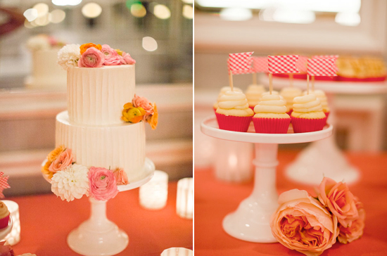 two-tiered white cake adorned with pink and gold flowers and checkered flag cupcake toppers