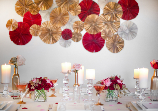 gold, red and silver paper wall decor, tapered glass candlesticks and pink and red roses