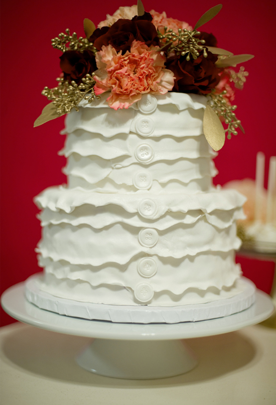 white ruffled cake with button accents and flower topper