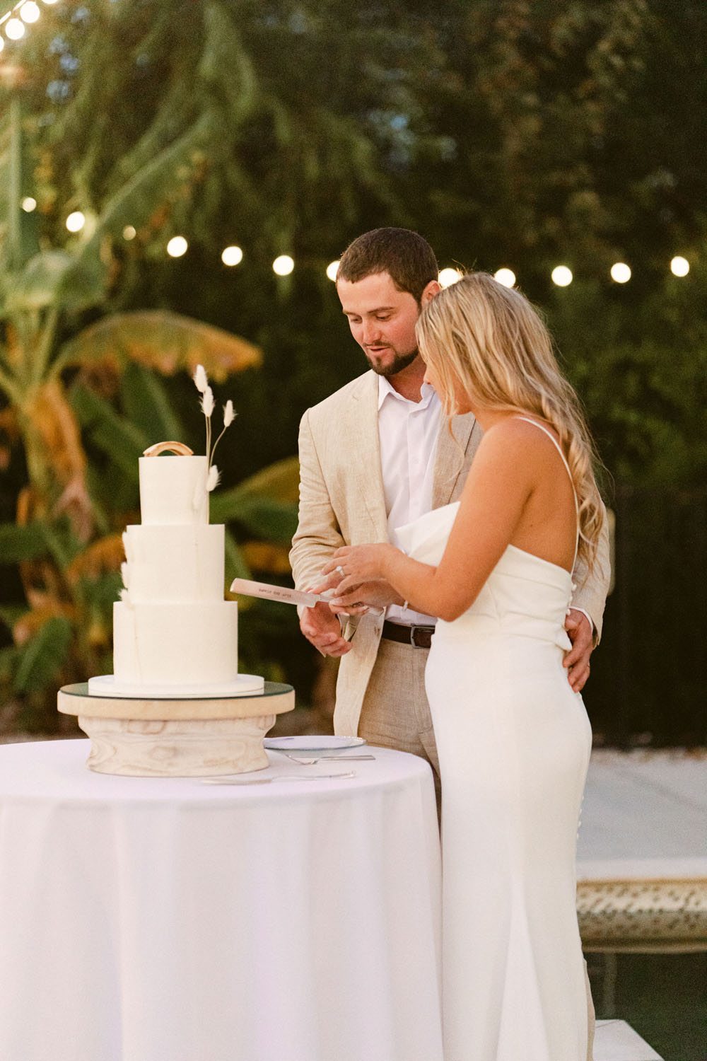 bride and groom cake cutting for all white wedding