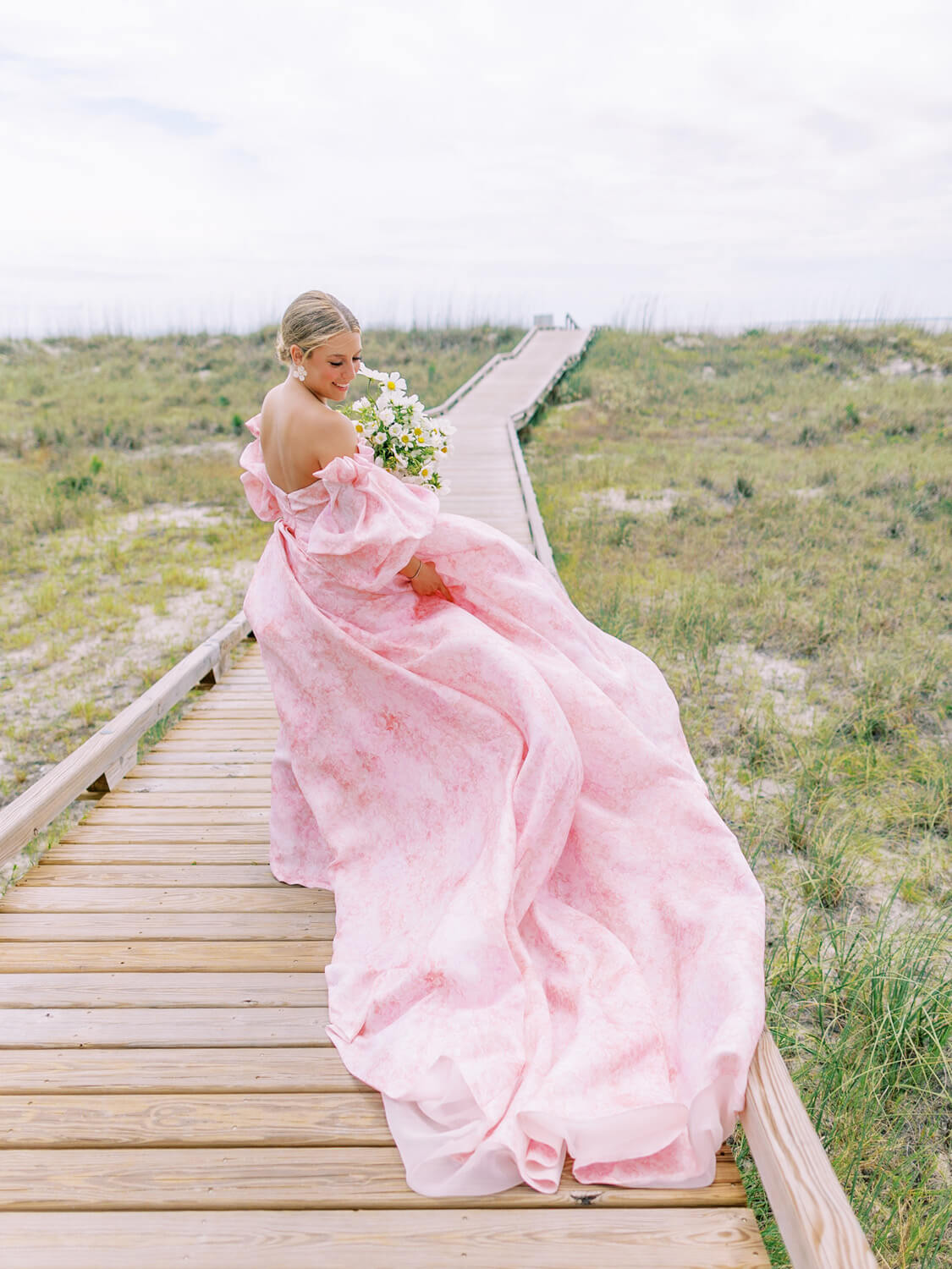 bride wearing monique lhuillier petal pink wedding dress at beachside wedding