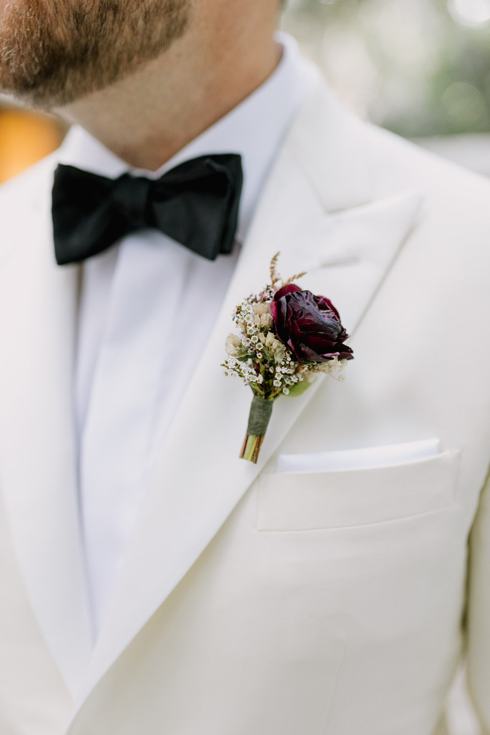 groom with white tux and black bowtie