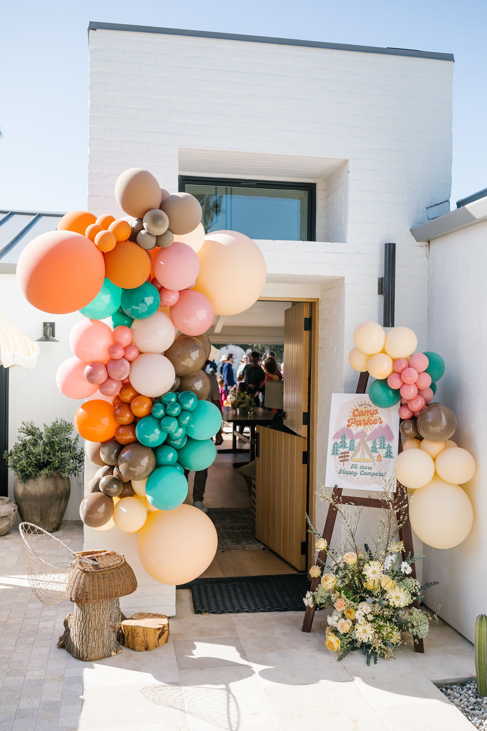 big colorful balloon decor and retro sign at camp themed party