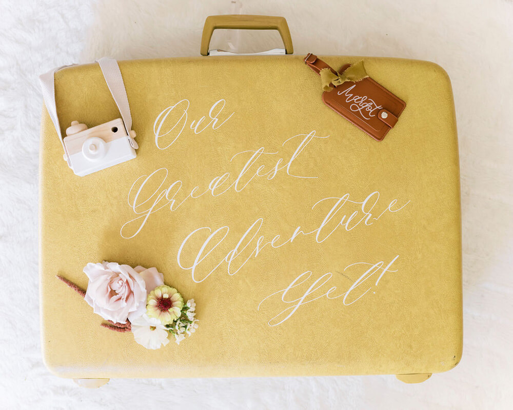calligraphy on suitcase for travel themed baby shower