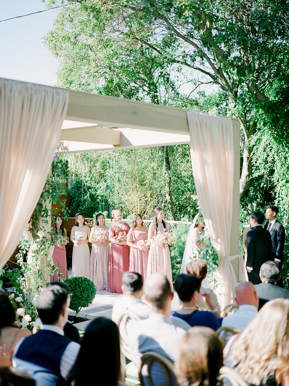spring backyard wedding ceremony with elegant draping and pink bridal party