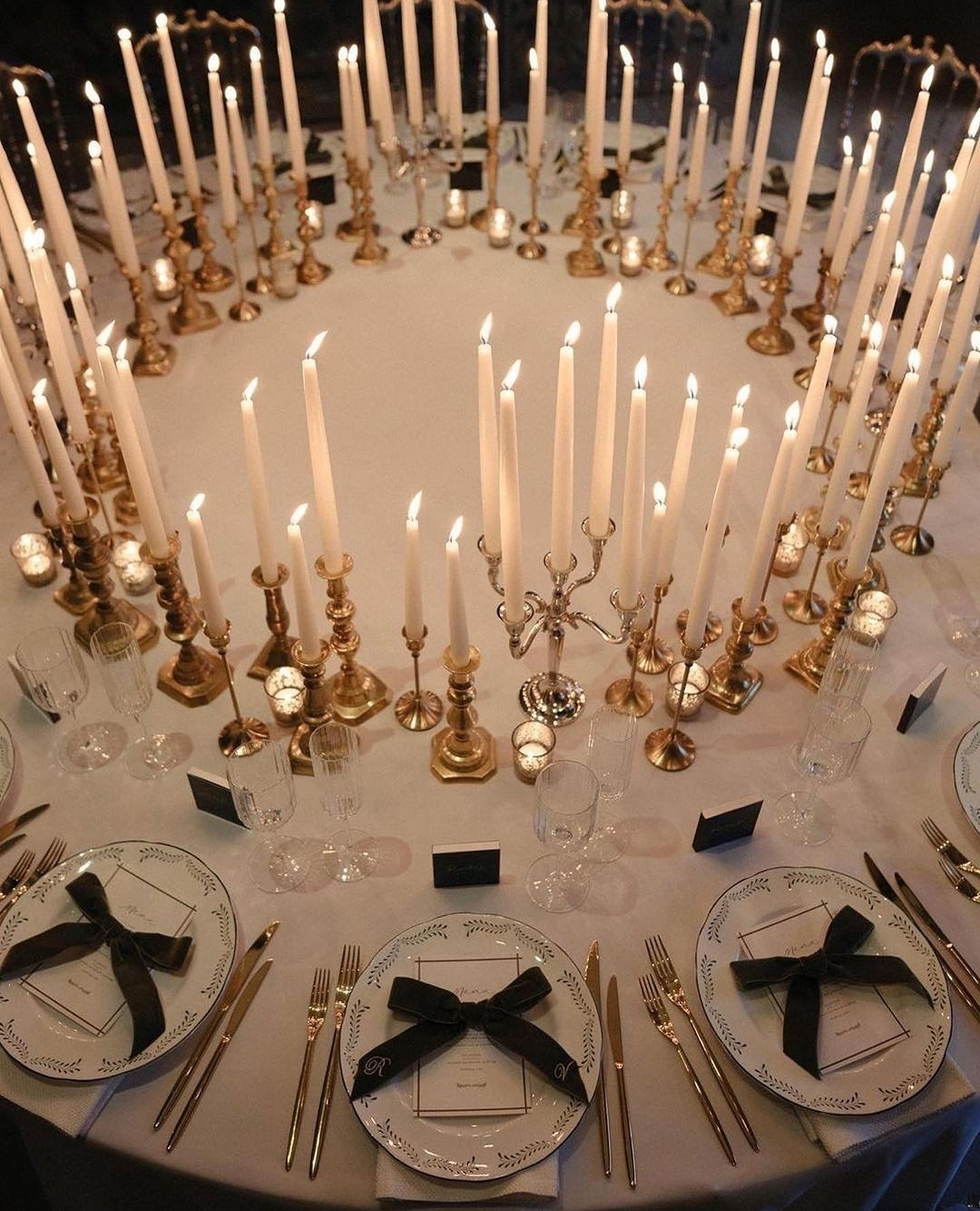 bow place settings and round candlelit dinner with gold candles from Charlotte Wise photography