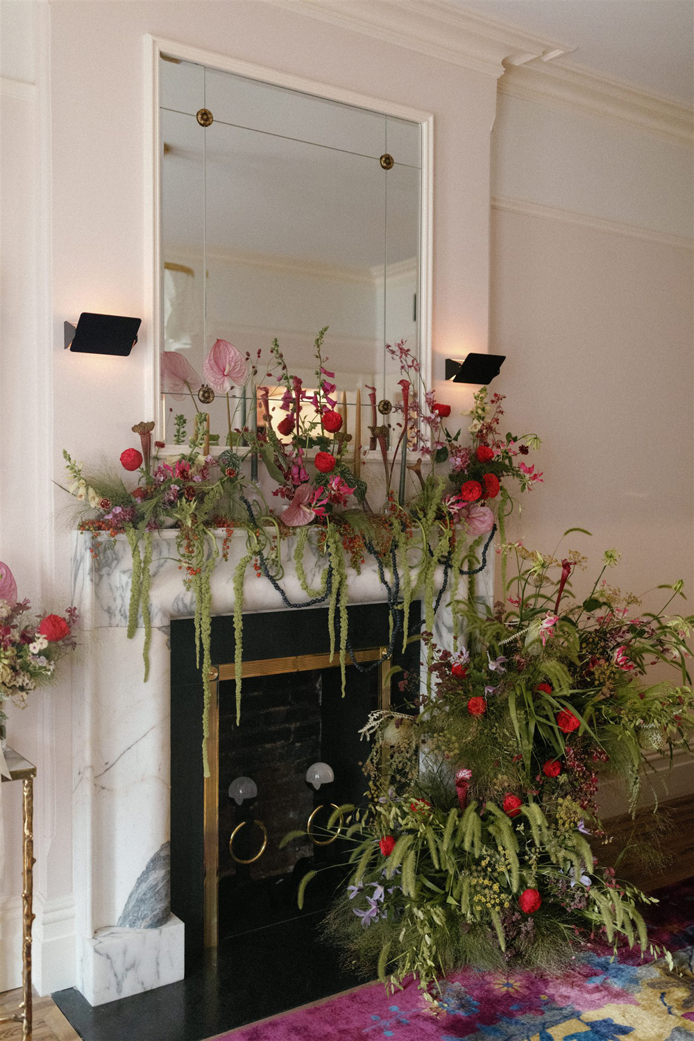 red, pink and green wedding flowers on mantel at hotel chelsea