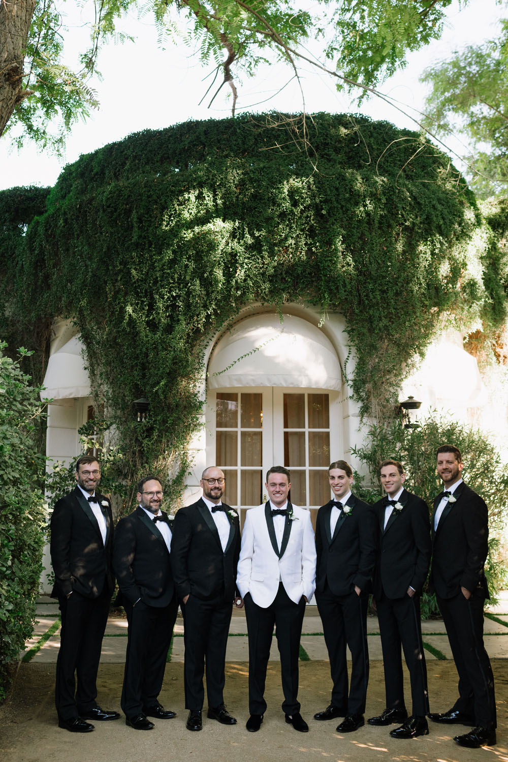 Groom in white tux jacket and groomsmen in black tuxes