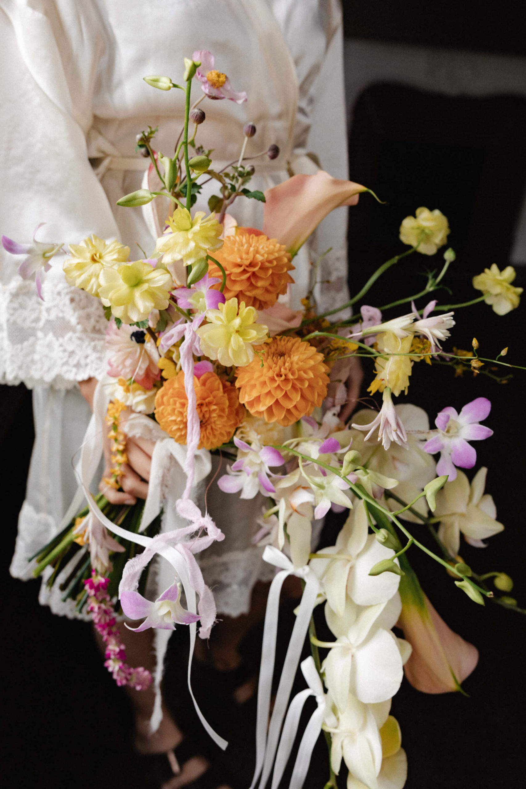 Bridal bouquet with colorful seasonal flowers in shades of peach, yellow, pink, and blue at a luxury wedding near Versailles.”