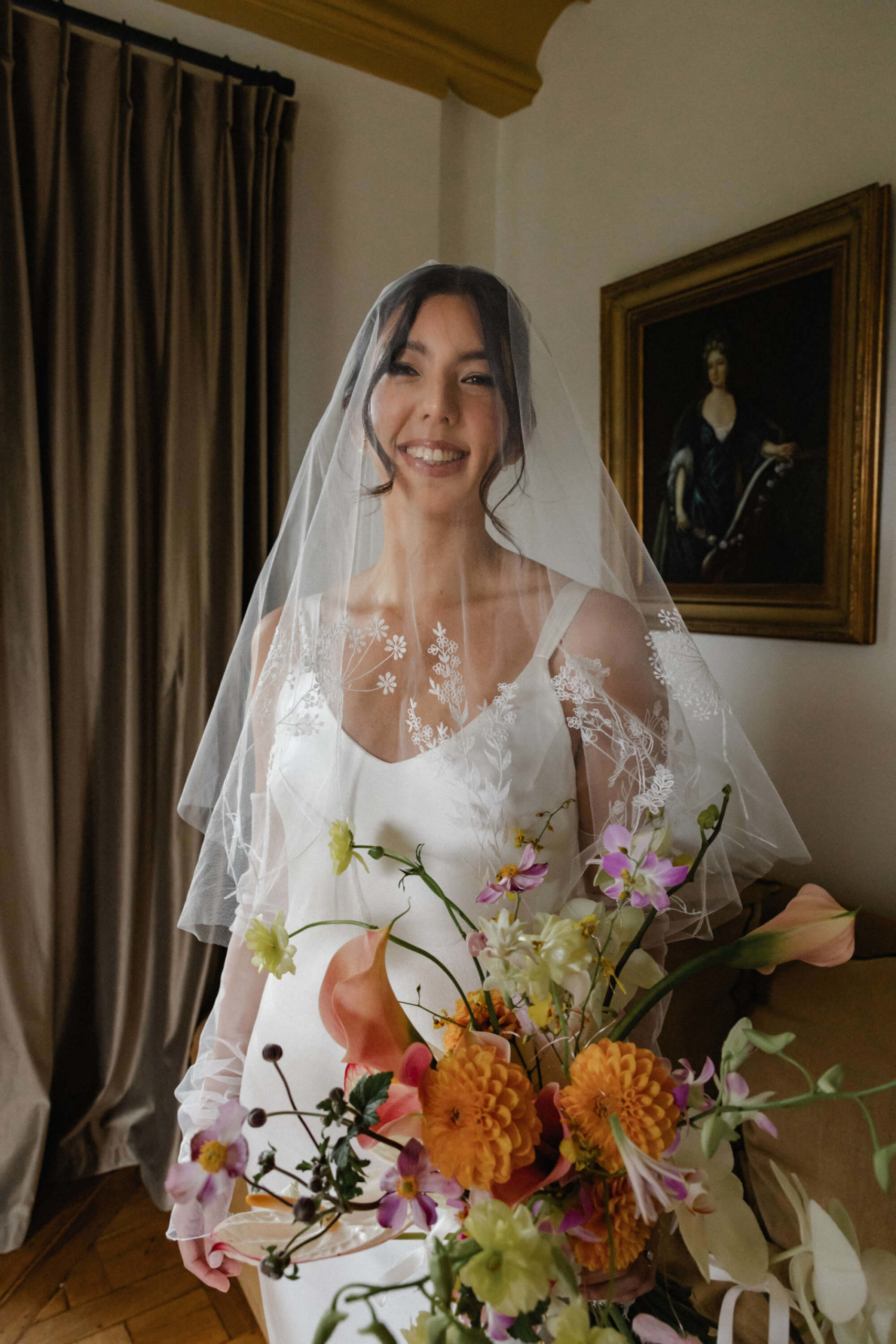 Elegant bride in a satin gown with a botanical embroidered veil at a destination wedding in France
