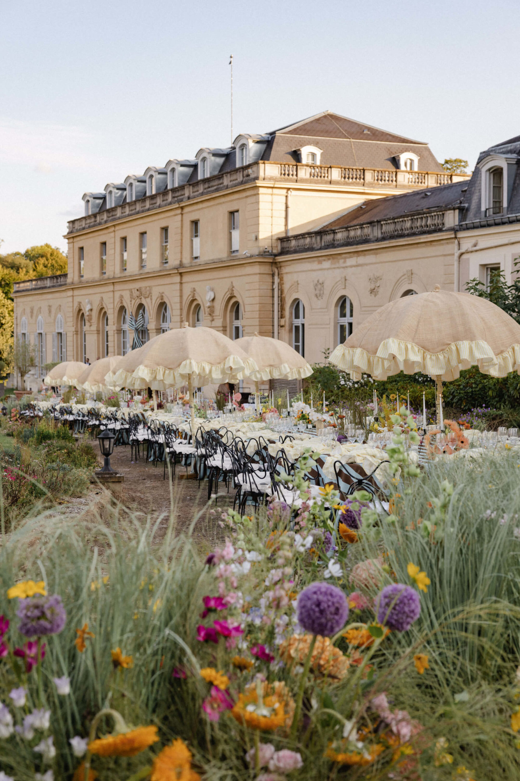 Outdoor wedding reception near Versailles with wicker fringe umbrella lamps and long dinner tables styled en plein air