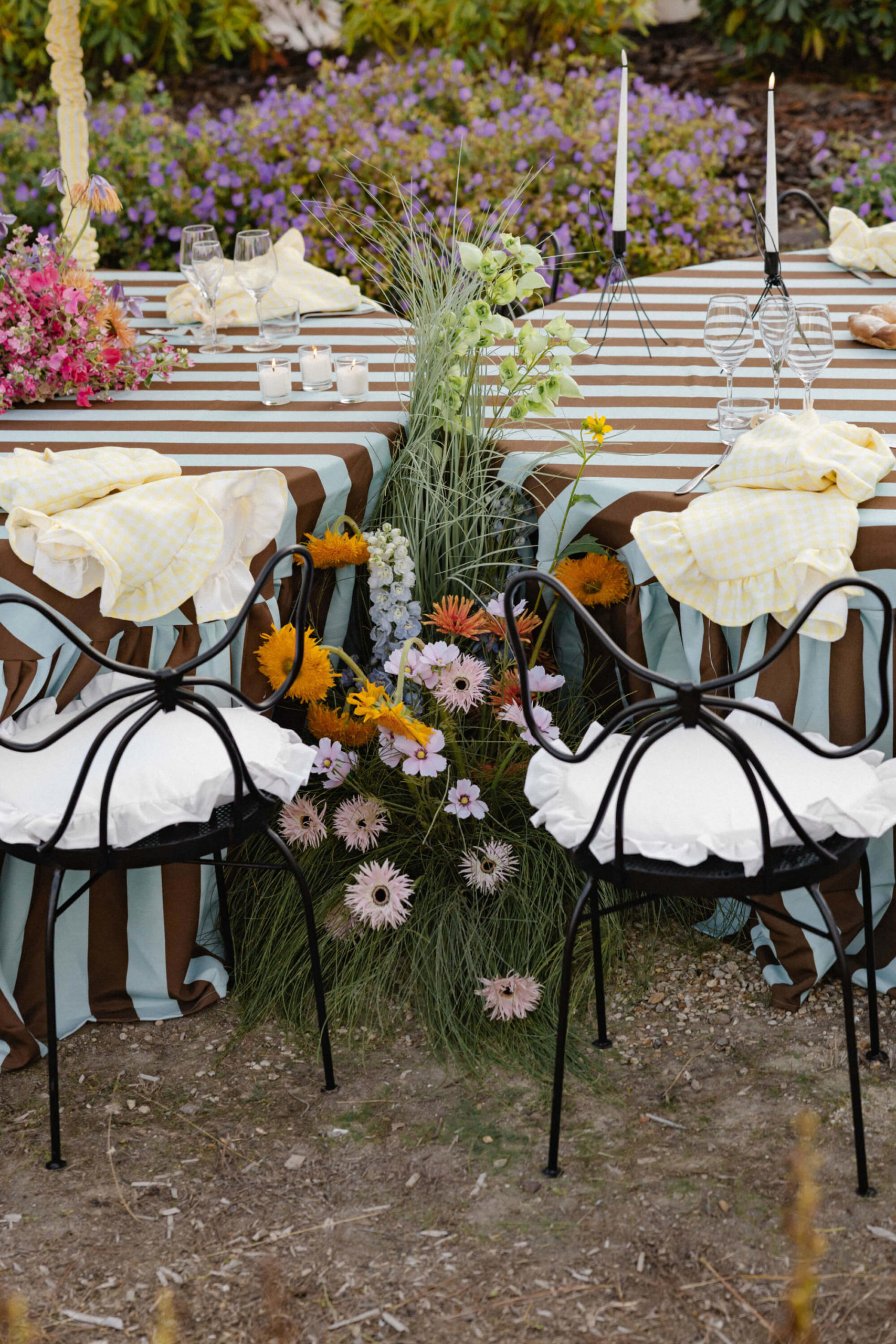 Custom black wrought-iron bow chairs at a destination wedding reception in the gardens of a château near Versailles.
