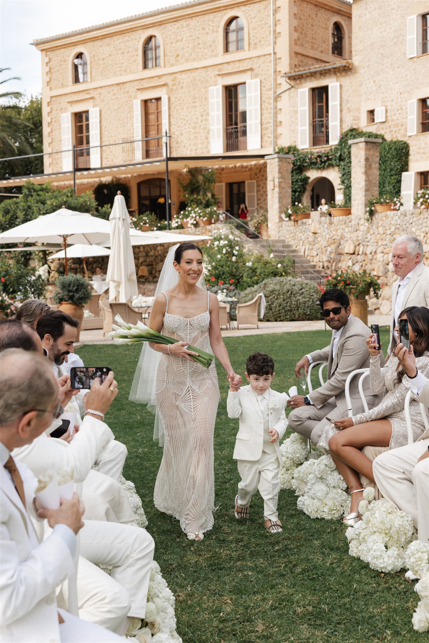 Bride walked down the aisle by her 3-year-old son toward groom holding their daughter