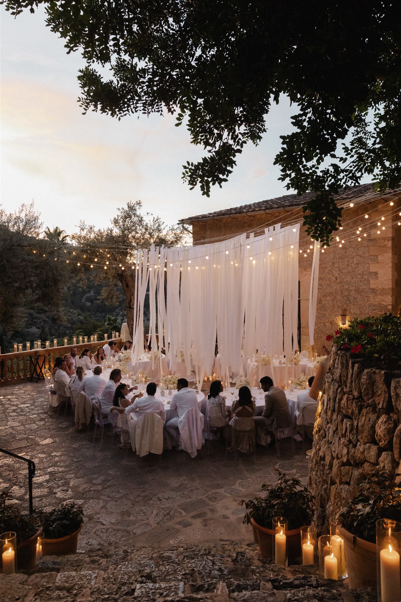 Outdoor Mallorca reception table styling in white linens, florals, and soft Mediterranean lighting