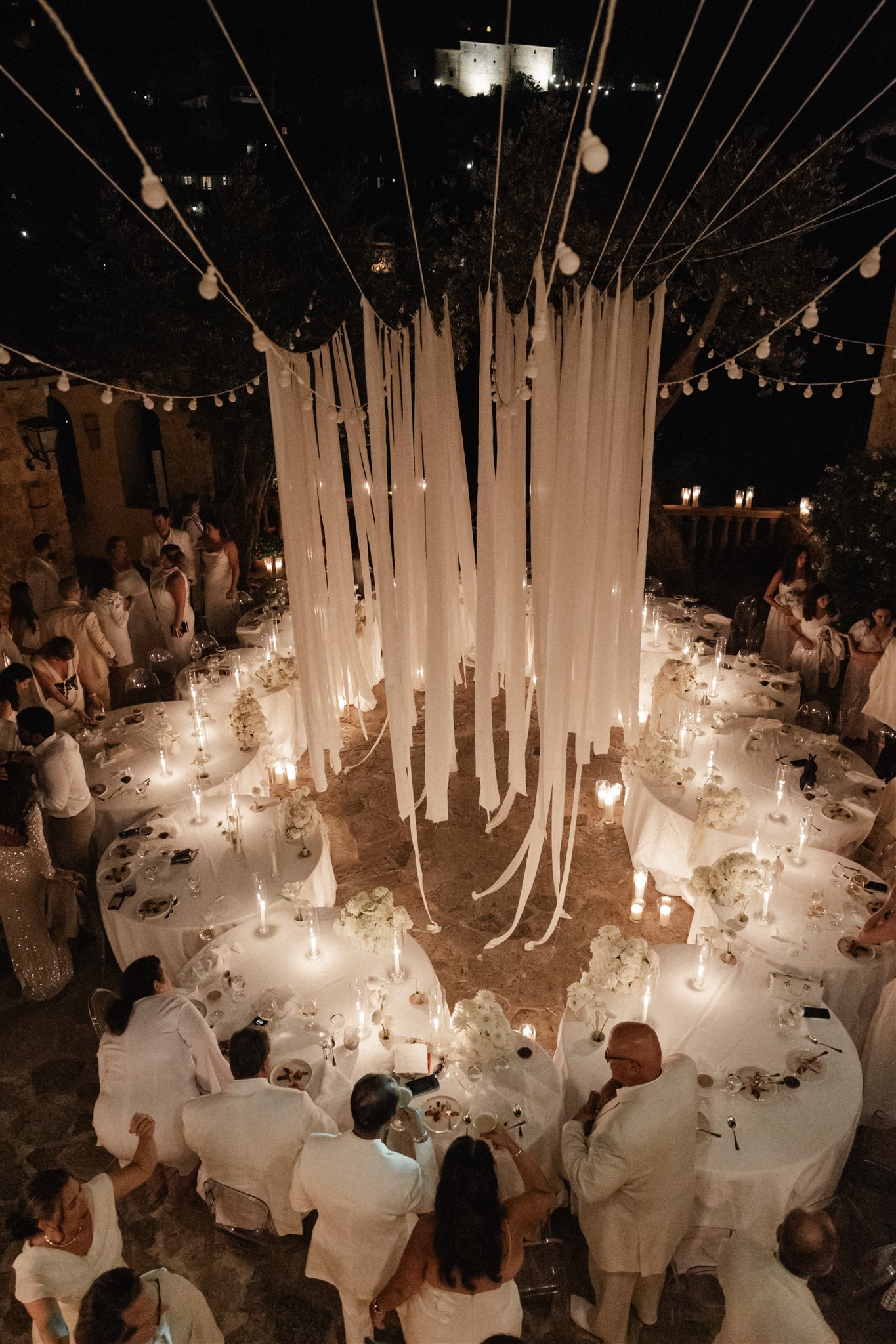 Outdoor Mallorca reception table styling in white linens, florals, and soft Mediterranean lighting