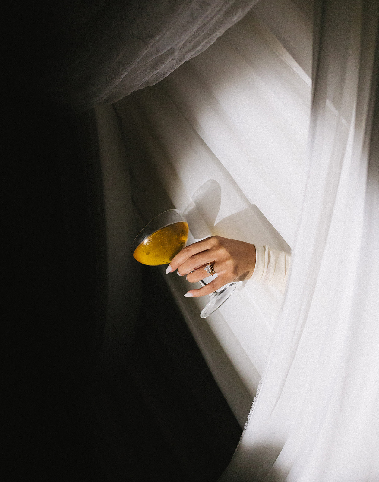 bride holding champagne near elegant draping