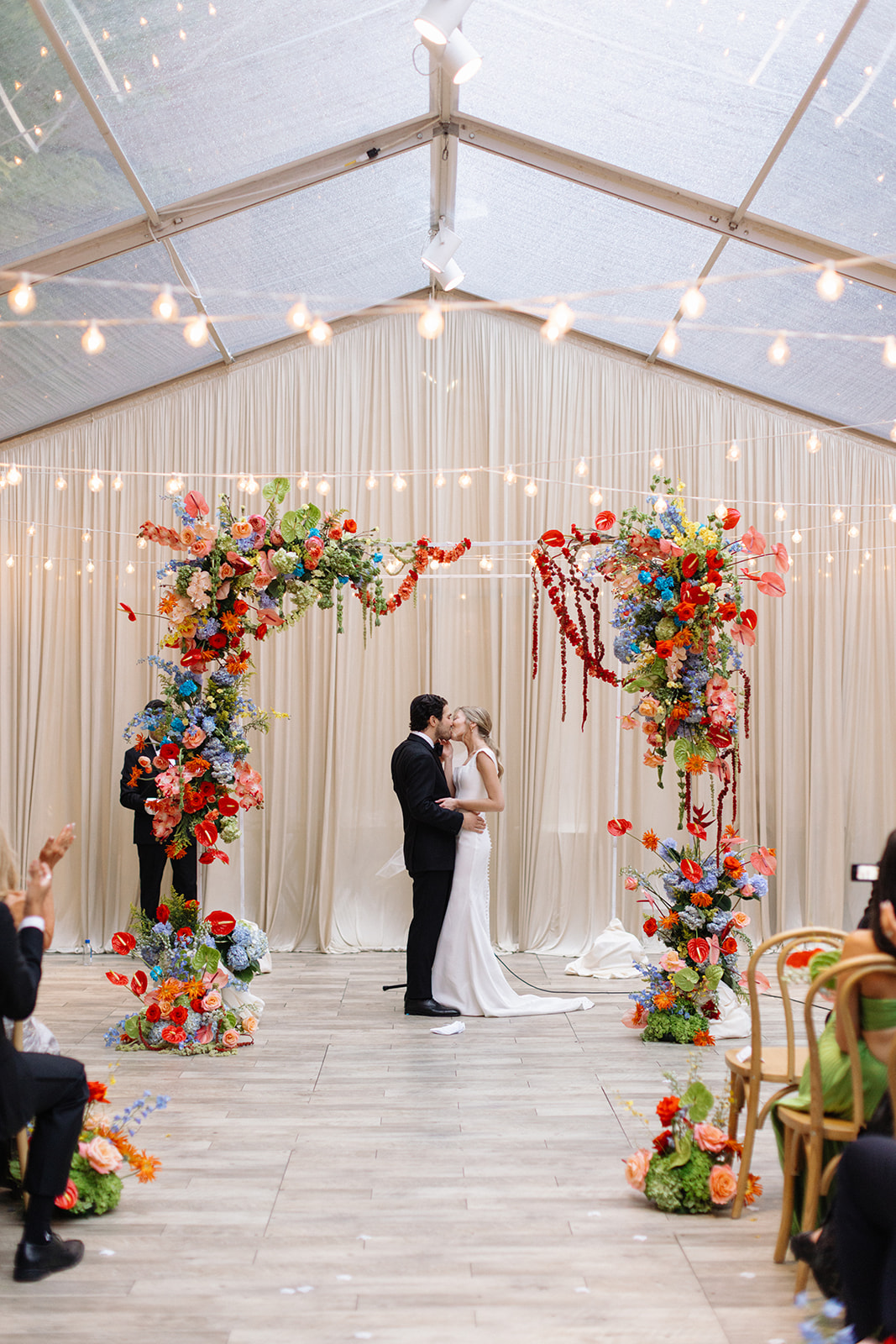 Outdoor tented wedding ceremony at The Chicago Illuminating Company in Chicago with vibrant citrus-colored florals and modern decor
