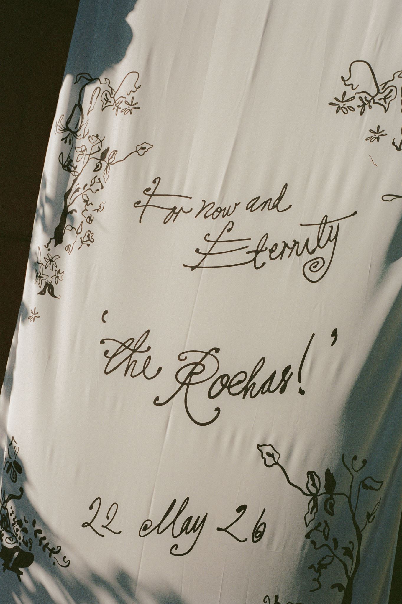 Hand-lettered wedding welcome sign hanging at the entrance of a pink Italian villa