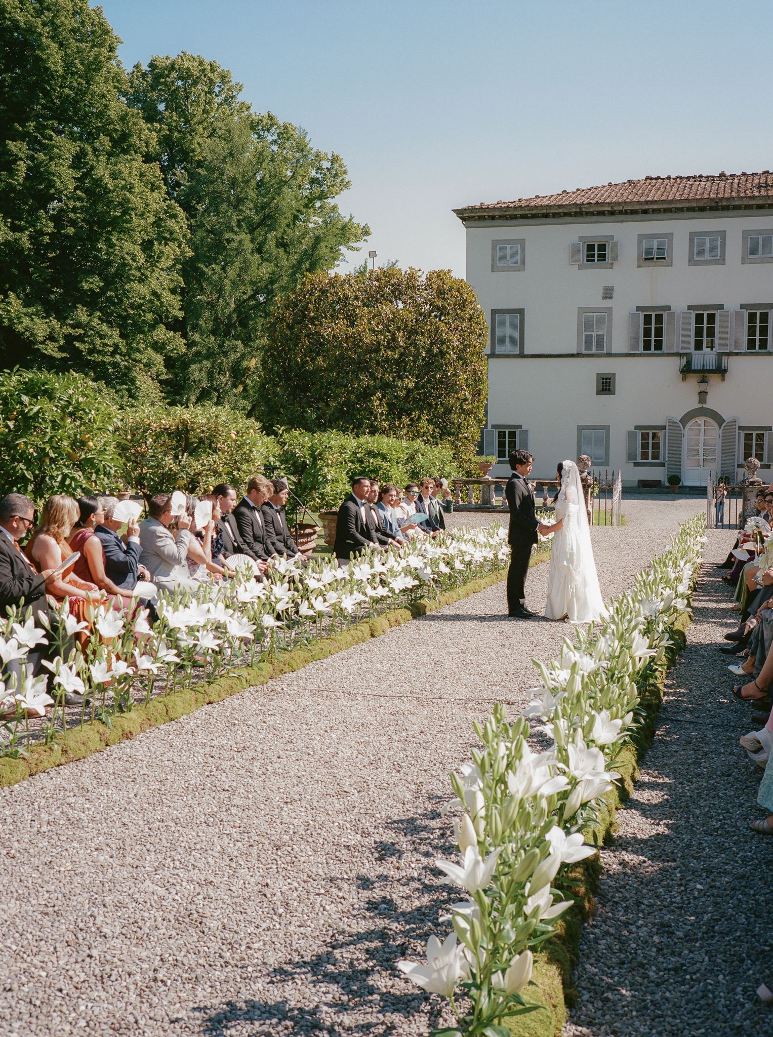 Natalia and Brandon exchange vows during a flower-lined outdoor ceremony in front of their historic Italian villa.