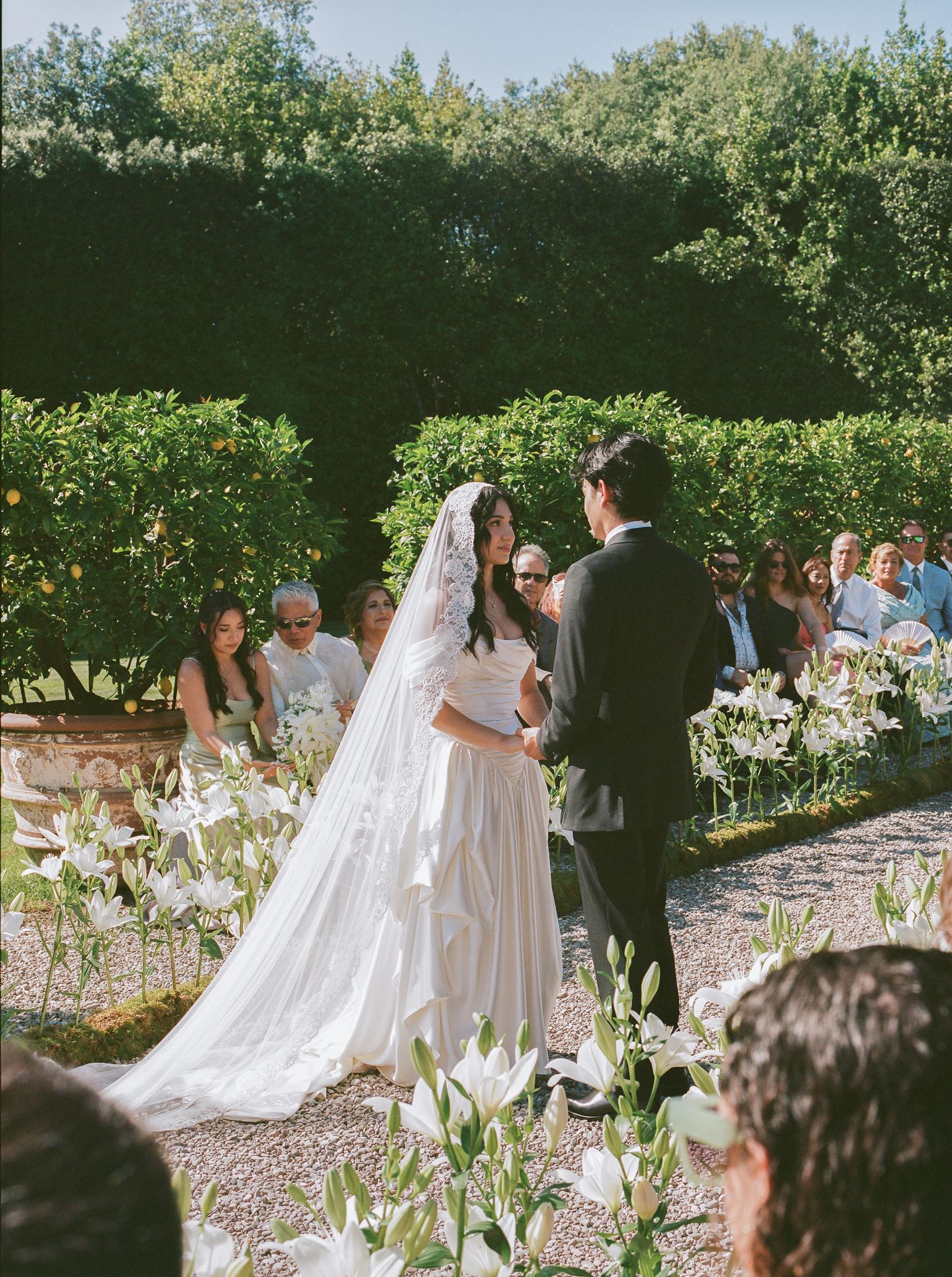 Bride and groom exchanging vows at an outdoor Italian villa wedding ceremony lined with white flowers