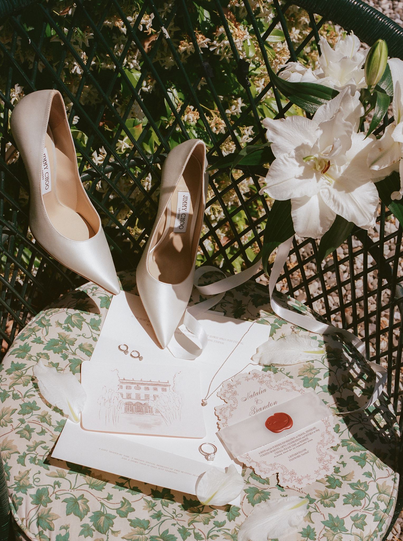 Jimmy Choo bridal shoes styled with wedding invitations, rings, jewelry, and white flowers