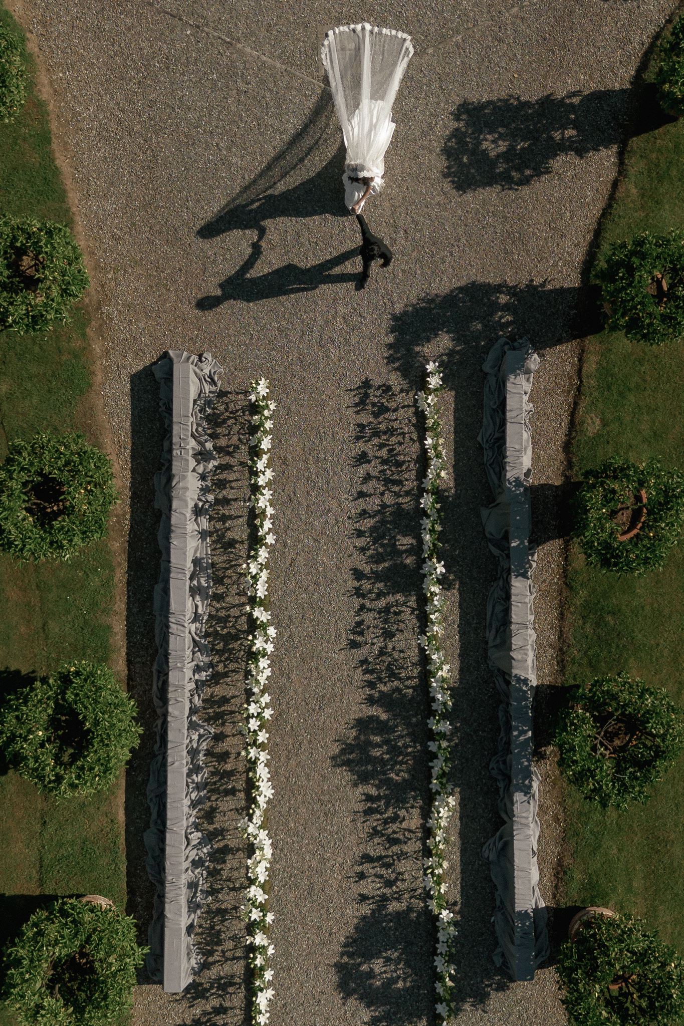 Bride walking down the aisle at an Italian villa wedding ceremony lined with white flowers