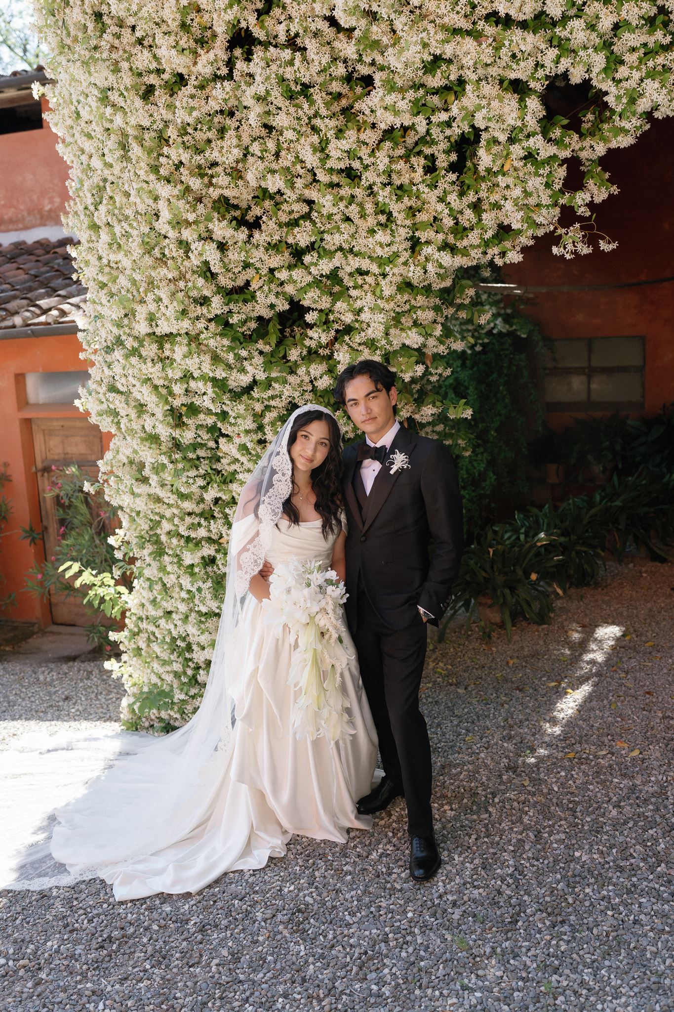 Bride and groom posing beneath a flowering tree at an Italian villa wedding