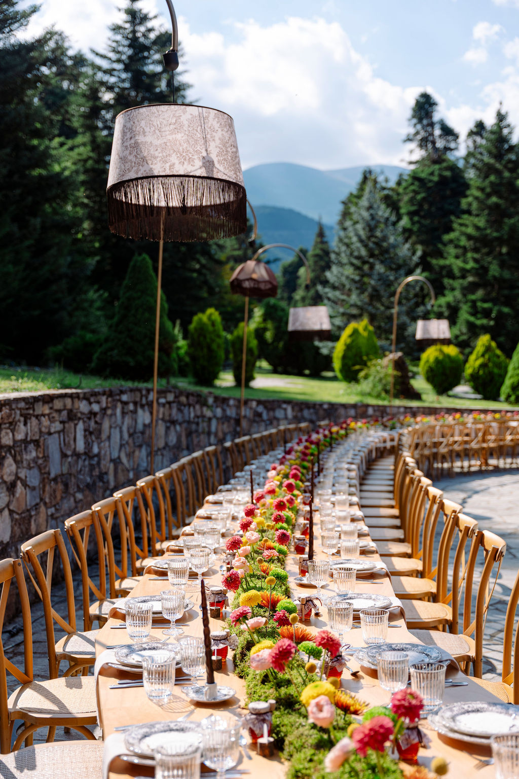 Guests seated at a long outdoor dinner table beneath the trees at a Mount Olympus wedding