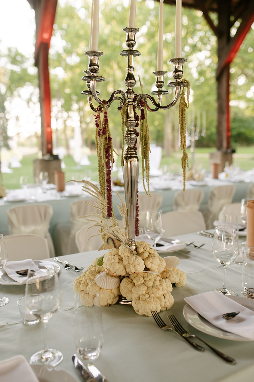 Romantic wedding reception table featuring an ornate gold candelabra, white linens, and ivory floral arrangements.