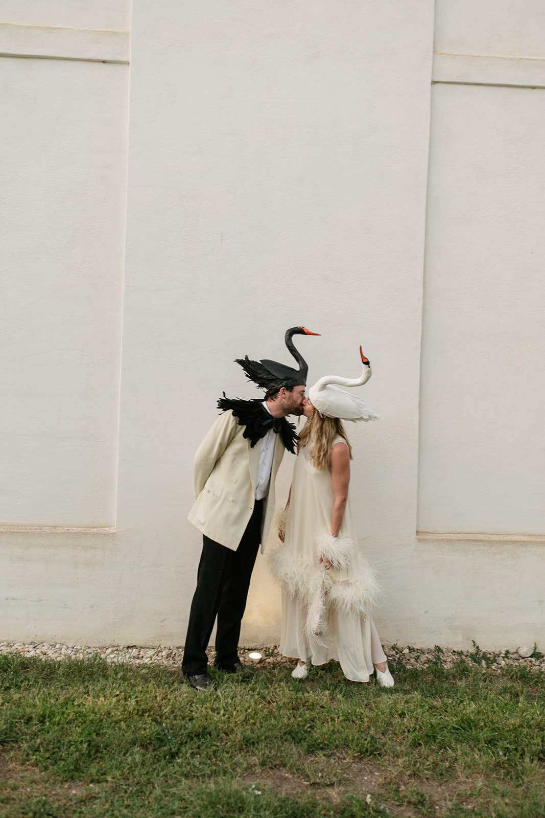 Artistic wedding portrait featuring oversized swan-inspired headpieces and avant-garde black-tie fashion.