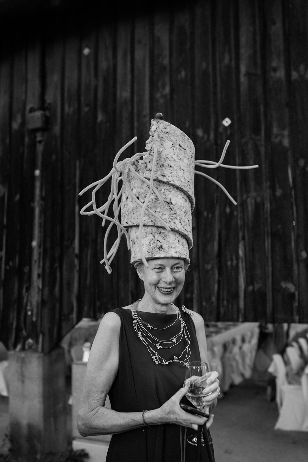 Black-and-white photograph of a wedding guest wearing a tall sculptural headpiece inspired by surrealist art.