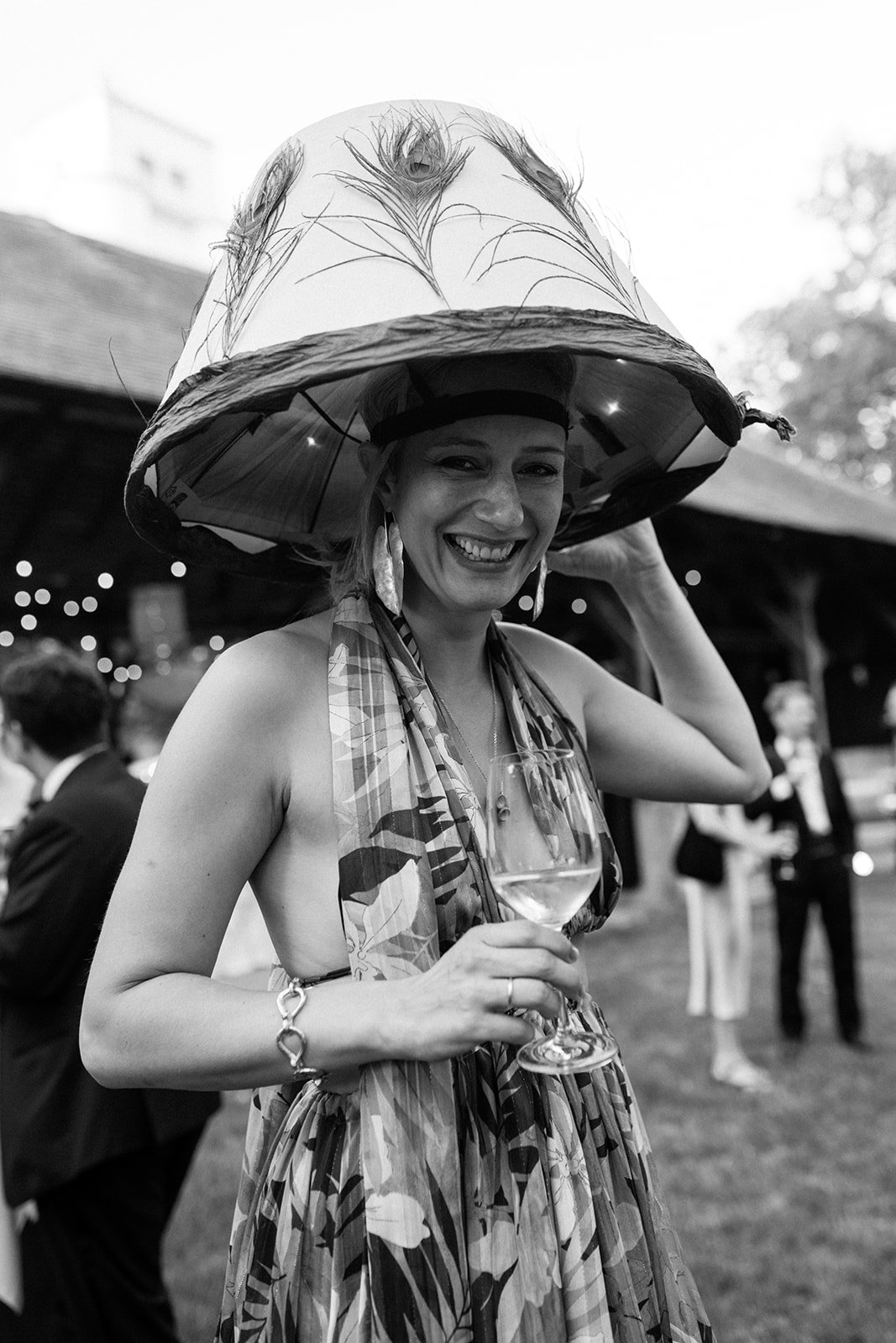 wedding guest wearing an oversized sculptural hat and patterned dress at an artistic wedding reception.