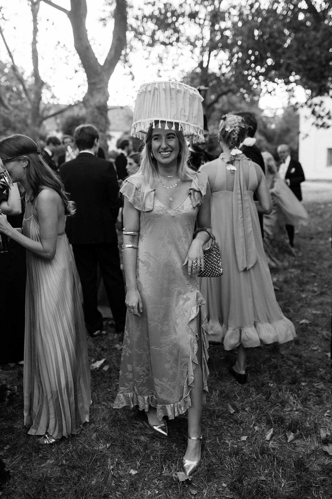 Black-and-white photograph of wedding guests wearing elaborate artistic headpieces and vintage-inspired eveningwear.